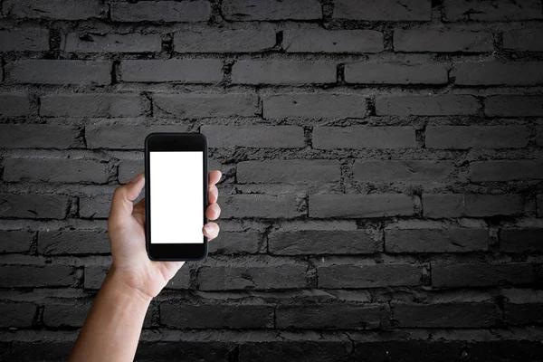 Homem segurando tela em branco de um smartphone no velho tijolo preto — Fotografia de Stock