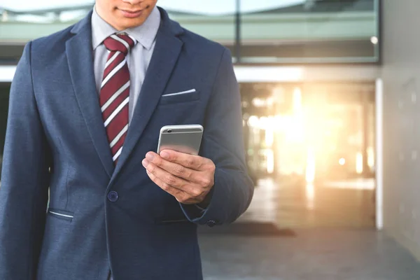 Um belo jovem empresário segurando enquanto usa seu telefone e s — Fotografia de Stock