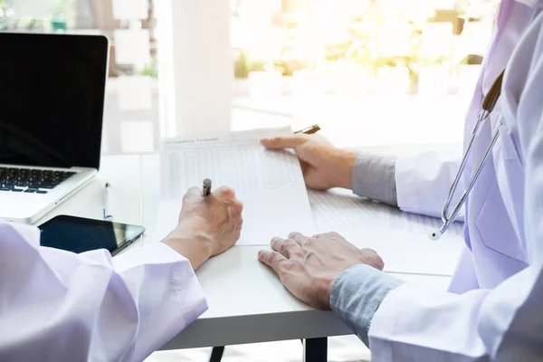 Dos doctores discutiendo la historia del paciente en un consultorio pointi — Foto de Stock