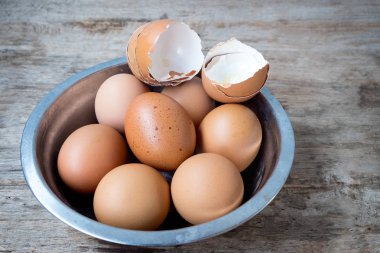 yumurta kabuğu ve ahşap arka plan üzerinde Metal Kupası'nda taze yumurta.