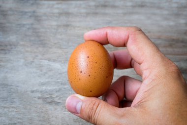 Yakın çekim el ahşap arka plan üzerinde yumurta yakalıyor