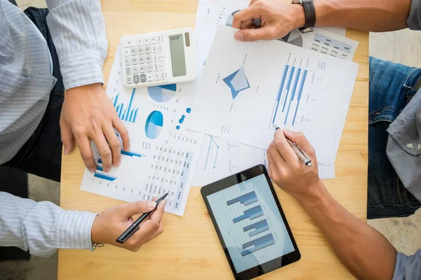 Two businessman calculating Tax Invoice, business strategy graph and using calculator on Wooden Desk, Coworker process.