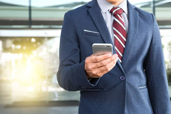 Um belo jovem empresário segurando enquanto usa seu telefone e s — Fotografia de Stock