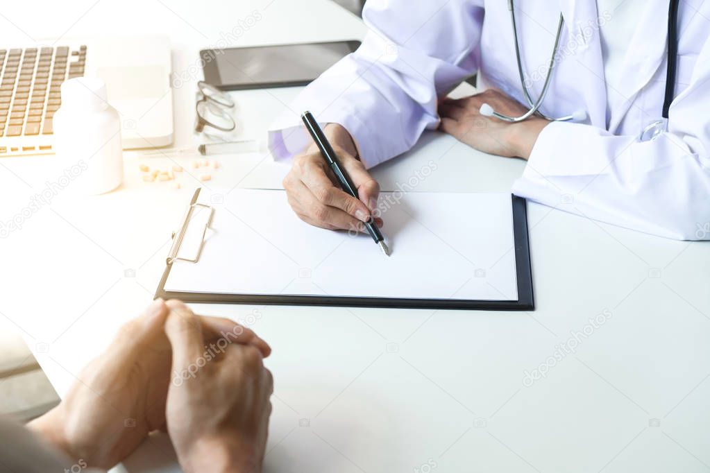 Healthcare and Medical concept, patient listening intently to a female doctor explaining patient symptoms or asking a question as they discuss paperwork together in a consultation.