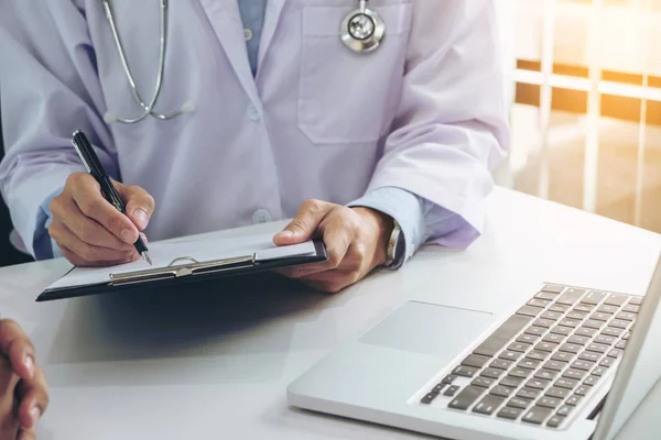 Close up of doctor filling up an history form while consulting patient and recommend treatment methods and how to rehabilitate the body. — Stock Photo, Image