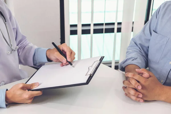 Primer plano del médico llenando un formulario de historial mientras consulta p —  Fotos de Stock