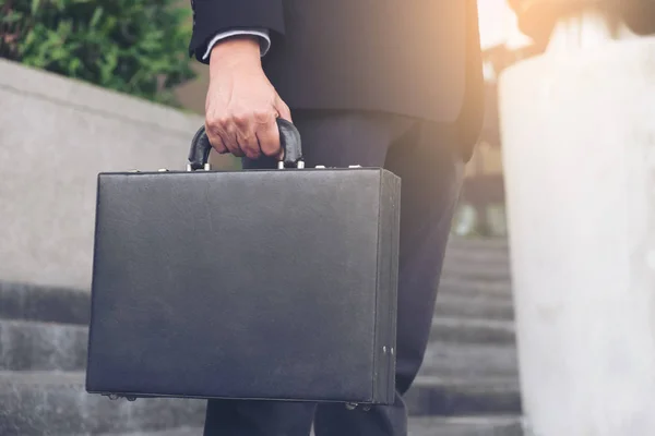 Бизнесмен, стоящий и держащий в руках портфель с рабочим остроумием — стоковое фото