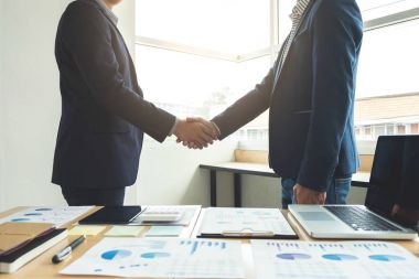 Bir toplantı sırasında el sıkışan iki iş adamı agreemen imzalamak