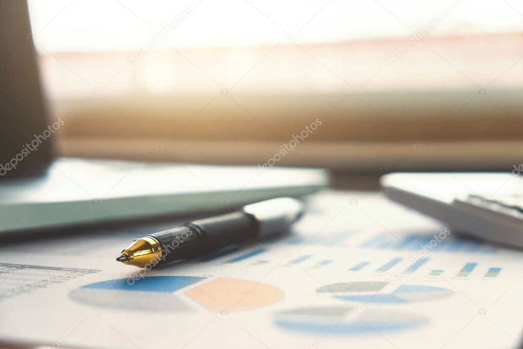 Close up of business pen and white calculator on financial graph