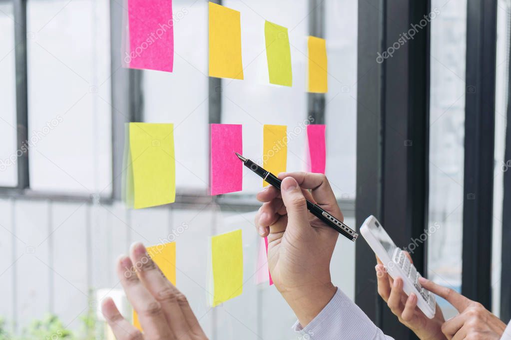 Young creative professional leader using post it notes in glass 