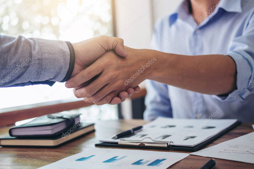 Two smiling businessman shaking hands together after good deal c