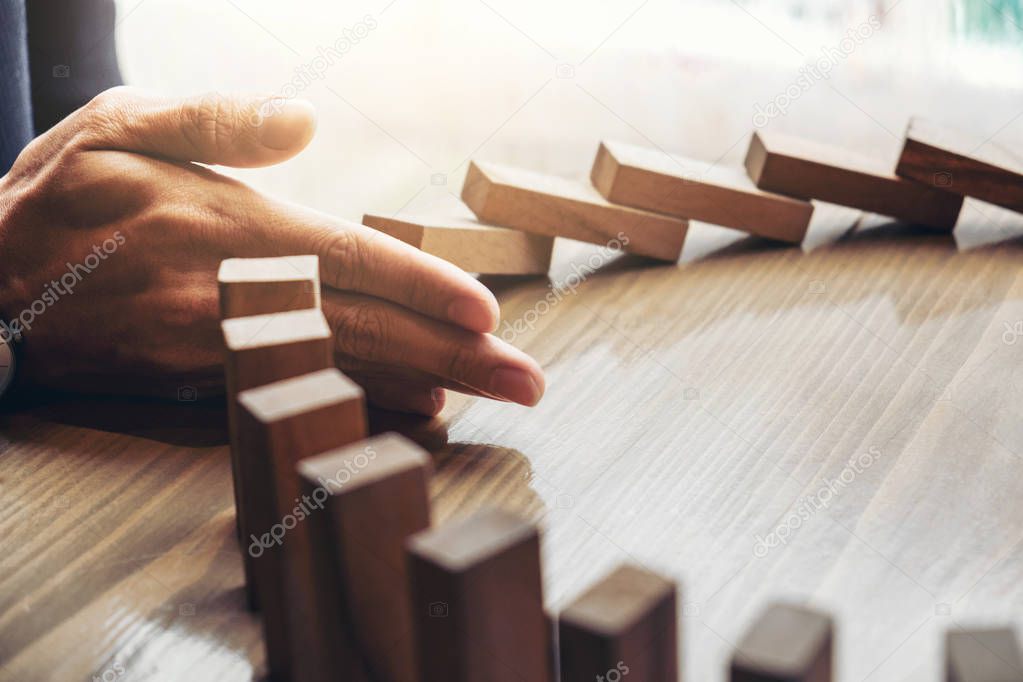 Close up of businessman hand Stopping Falling wooden Dominoes ef