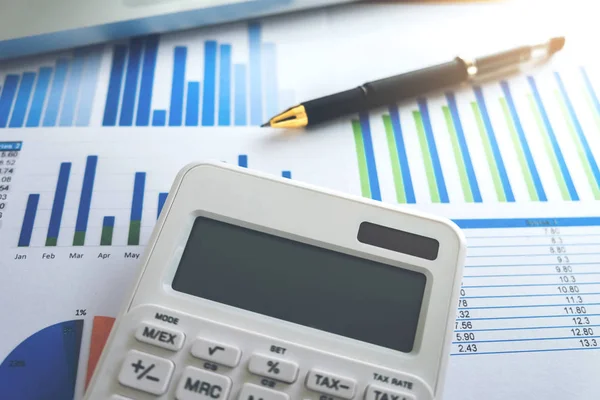 Close up of business pen and white calculator on financial graph — Stock Photo, Image