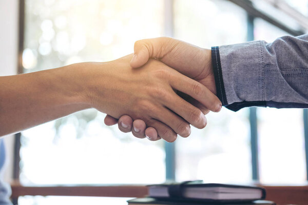 Two smiling businessman shaking hands together after good deal c