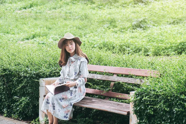 Atractiva mujer asiática leyendo un libro y relajándose en el parque — Foto de Stock