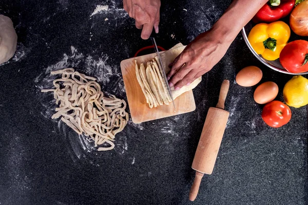 Vrouwelijke huisvrouw maken van huisgemaakte pasta met bloem en eieren over — Stockfoto