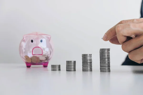 Affärsman sättande mynt öka tillväxten på ett skrivbord och en piggy — Stockfoto