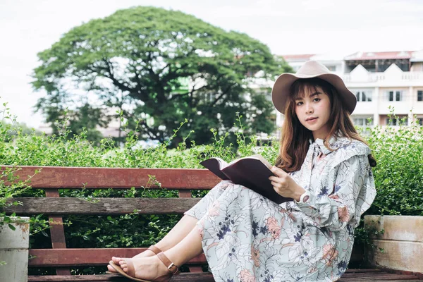 Atractiva mujer asiática leyendo un libro y relajándose en el parque — Foto de Stock