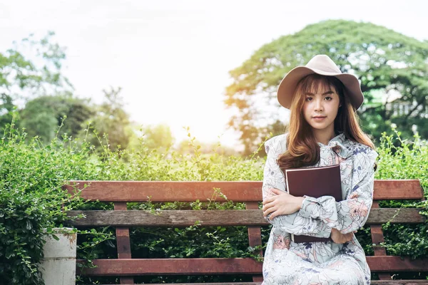 Atractiva mujer asiática leyendo un libro y relajándose en el parque — Foto de Stock