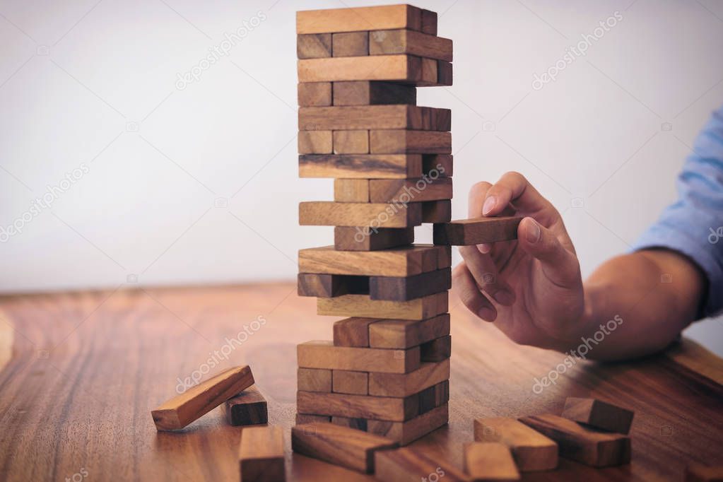 Images of hand of businesspeople placing and pulling wood block 
