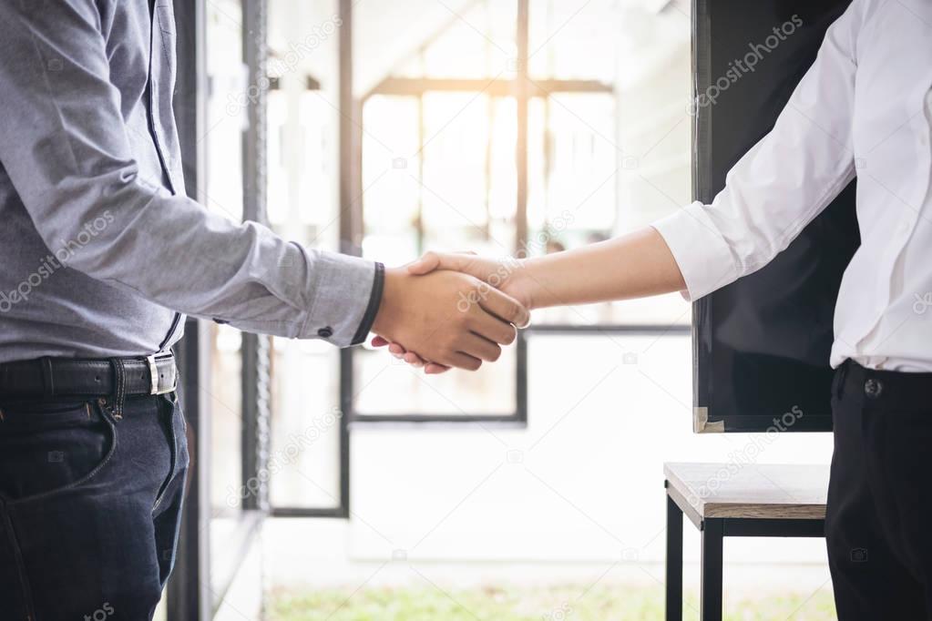 Two businesspeople shaking hands during a meeting in the office,