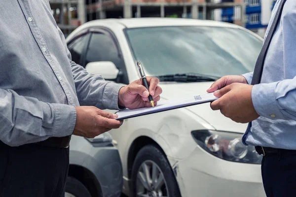 Verzekeringsagent onderzoeken auto beschadigd en klant signatur indienen — Stockfoto