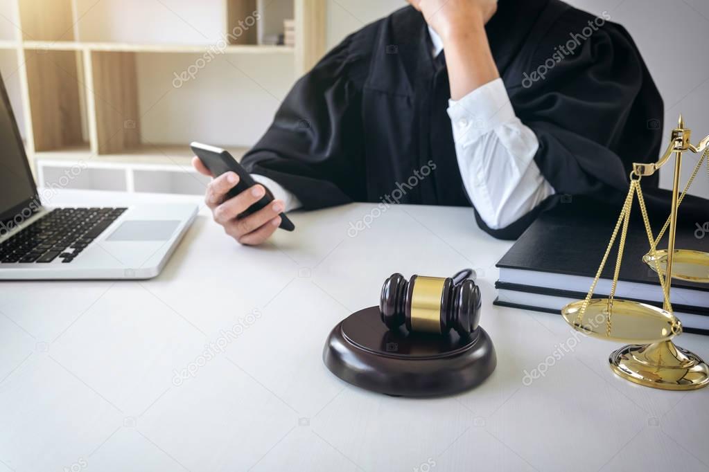 Male lawyer or judge working with smart phone and scales of just
