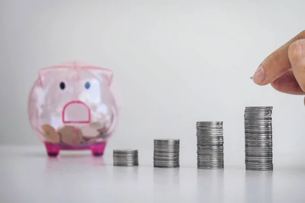 Empresario poner monedas aumentar el crecimiento en un escritorio y un cerdito — Foto de Stock