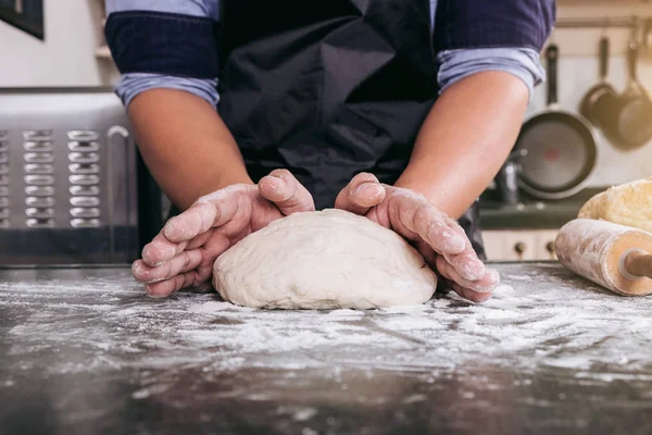 Mannelijke handen kneden van deeg besprenkeld met bloem tabel, prep handen — Stockfoto