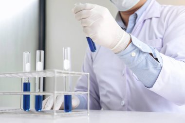 Bilim adamı veya tıbbi laboratuar önlüğünü tüp ile reaktif holding içinde,