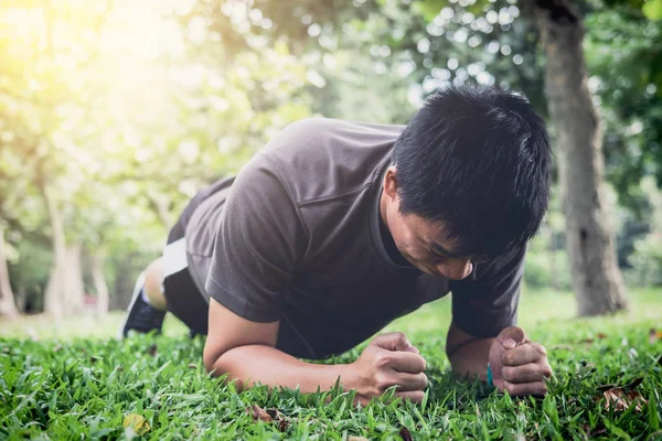 夏の公園の芝生の上の外板張りを行うトレーニング フィットネスを行使若い男 — ストック写真