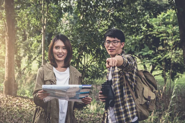 Two Young Traveler with backpack, are holding map relaxing in gr