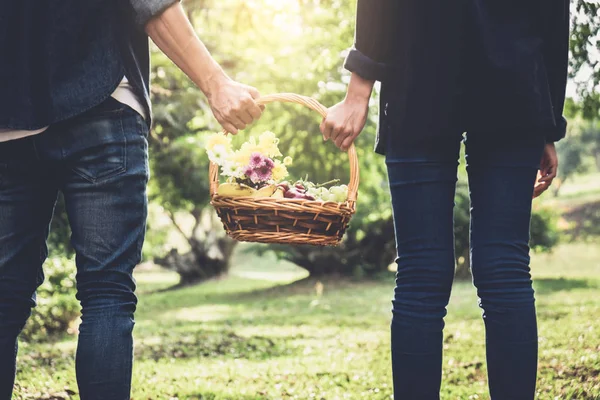 Casal apaixonado andando e segurando uma cesta de piquenique na natureza — Fotografia de Stock