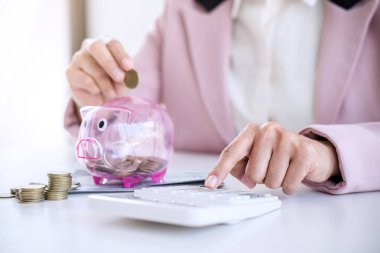 Kumbara para koyarak ve calculato kullanarak iş kadını