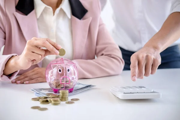 Two couples putting coins into piggy bank, writing to report and — Stock Photo, Image
