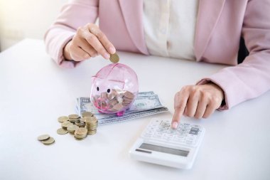 Kumbara para koyarak ve calculato kullanarak iş kadını
