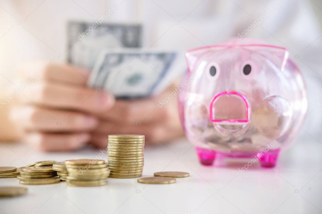 Businessman putting coins into piggy bank and using calculator t