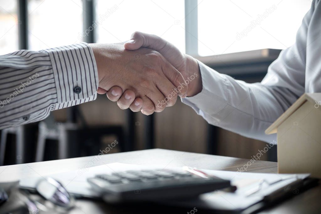 Real estate broker agent and customer shaking hands after signin