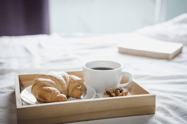 Kruvasan ve kahve sabah fincan eski kitap ile yatakta