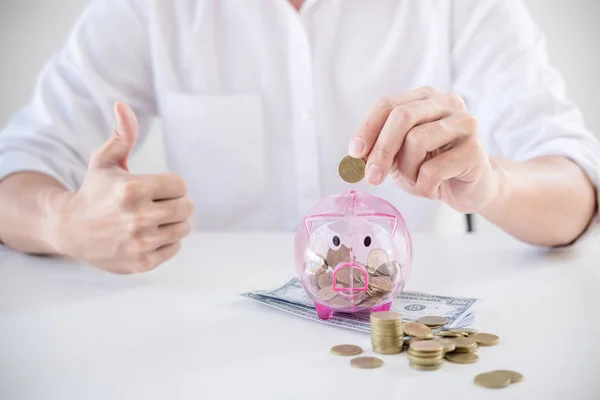 Empresario poniendo monedas en alcancía y utilizando la calculadora t — Foto de Stock