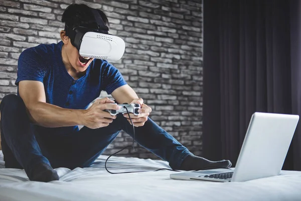 Mladý muž se bavit na ložnici v soupravu pro virtuální realitu nebo 3d g — Stock fotografie