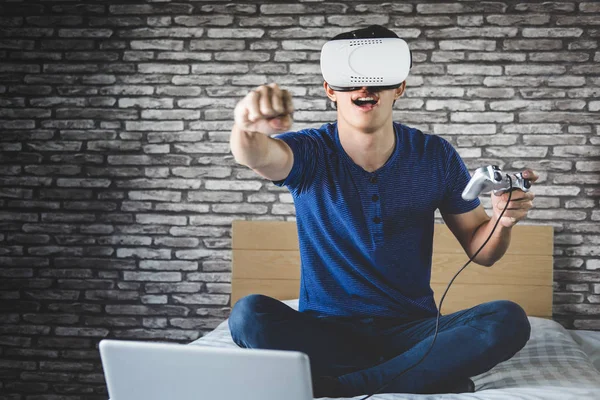 Hombre joven con auriculares de realidad virtual o gafas 3D jugando video —  Fotos de Stock