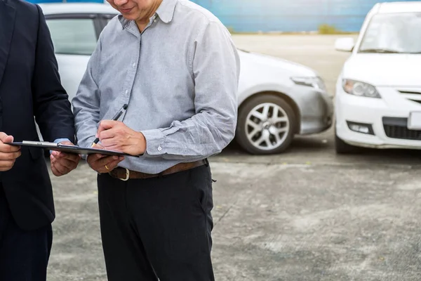 Verzekeringsagent onderzoeken auto beschadigd en klant signatur indienen — Stockfoto