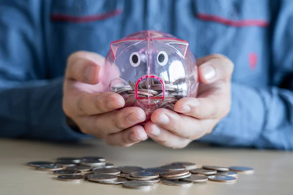 Homem colocando moedas em porquinho banco com poupança e análise busi — Fotografia de Stock