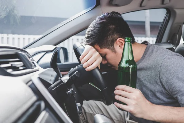 Joven asiático hombre conduce un coche con borracho un botella de cerveza y fal —  Fotos de Stock