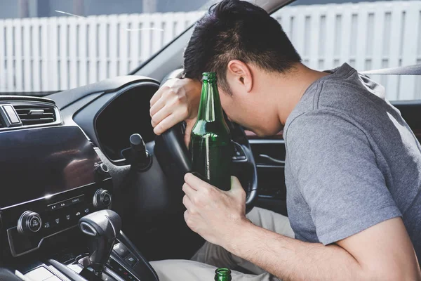 Joven asiático hombre conduce un coche con borracho un botella de cerveza y fal —  Fotos de Stock