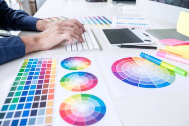 İş yerinde iş araçları ve aksesuarlarıyla renk seçimi ve grafik tableti üzerinde çalışan erkek yaratıcı grafik tasarımcı resmi.