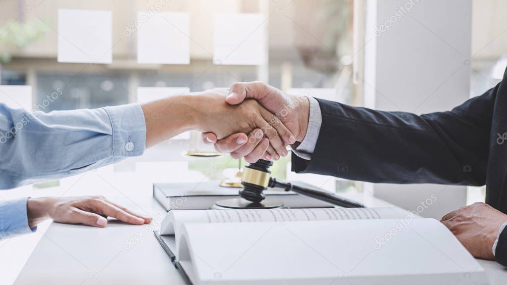 Handshake after good cooperation, Businesswoman Shaking hands with Professional male lawyer after discussing good deal of contract in courtroom, Concepts of law, Judge gavel with scales of justice.