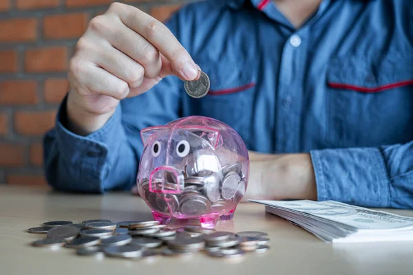 Homem colocando moedas em porquinho banco com poupança e análise busi — Fotografia de Stock