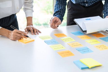 Buluşan ve planlayan iki yaratıcı iş adamı, fikir, analiz veri grafiği ve çalışma stratejisi ile ofis içinde beyin fırtınası yapmak için masaya yapışkan notlar bırakırlar..